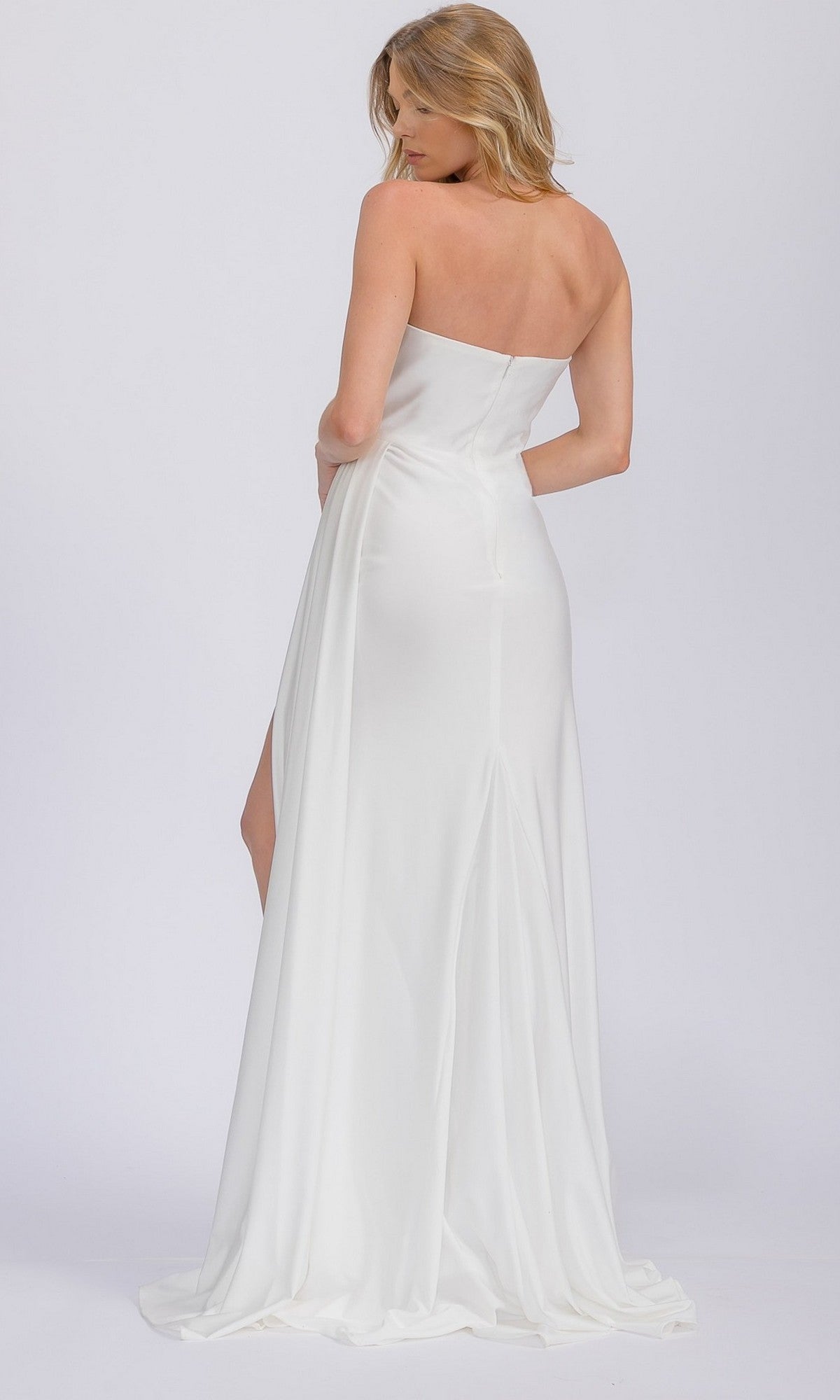 A woman wearing the Eureka EK178 long prom dress, a strapless floor-length white gown, stands with her back turned and looks over her shoulder against a plain light background.